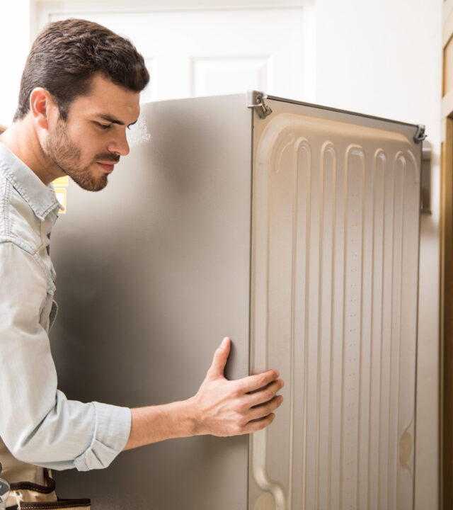 Electrician moving a fridge in a kitchen Trusted LG Refrigerator Repair & Service Technicians Across UAE
